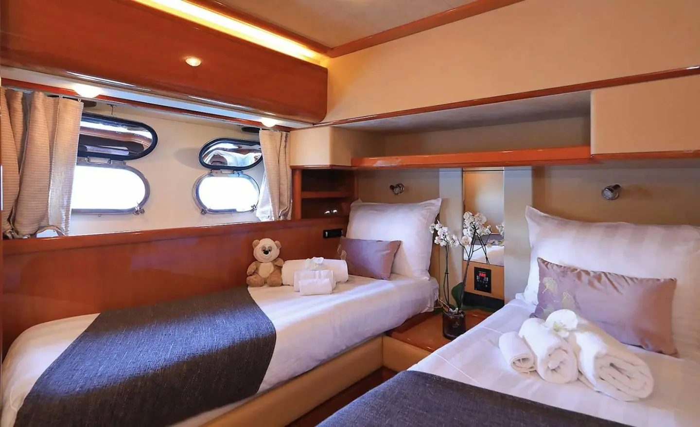 Interior of Quo Vadis I yacht with twin beds, wood accents and porthole window