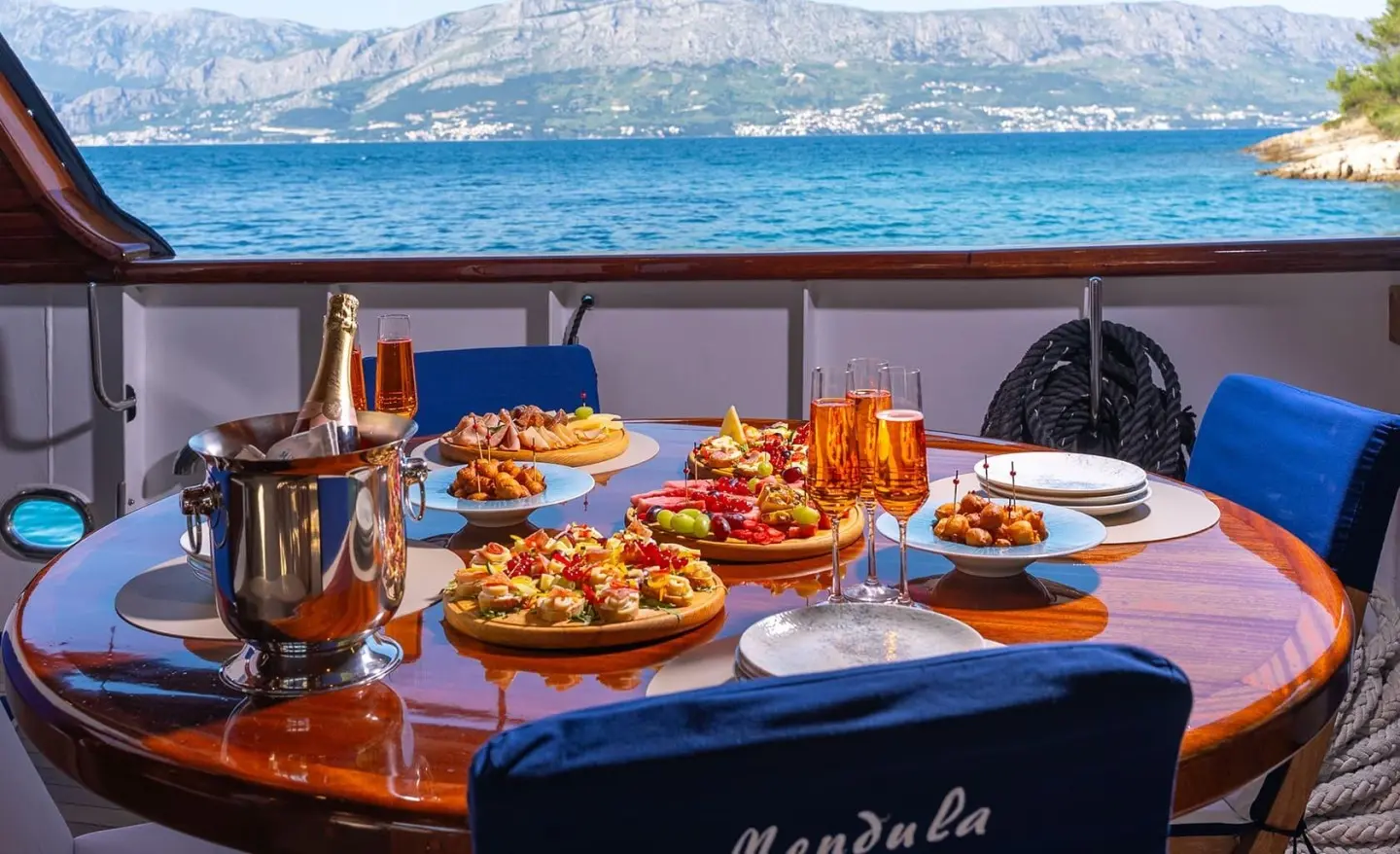 Mendula yacht dining table on deck with sunset ocean view and plates