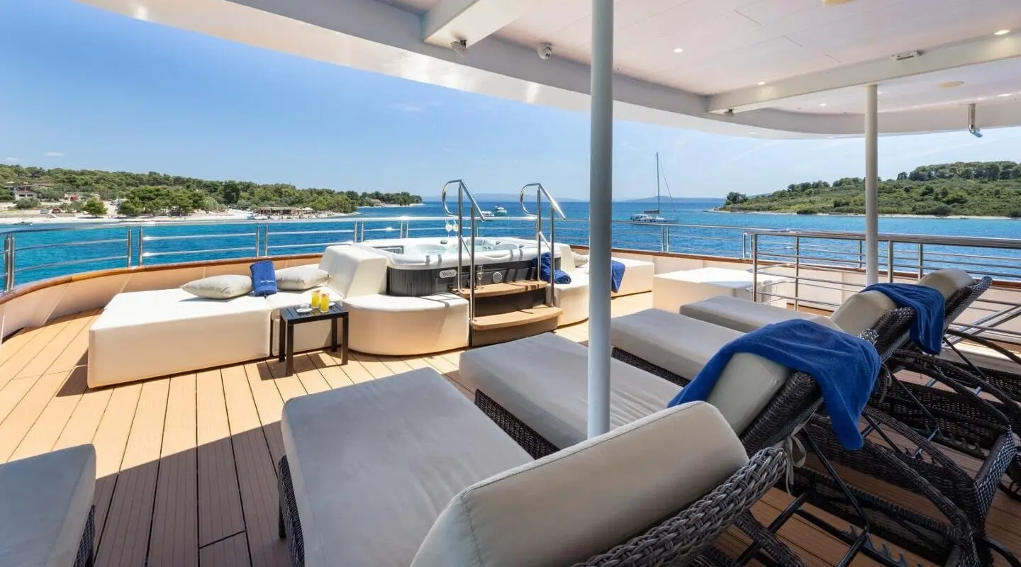 Deck vantage of Queen Eleganza with seating, table, and ocean view
