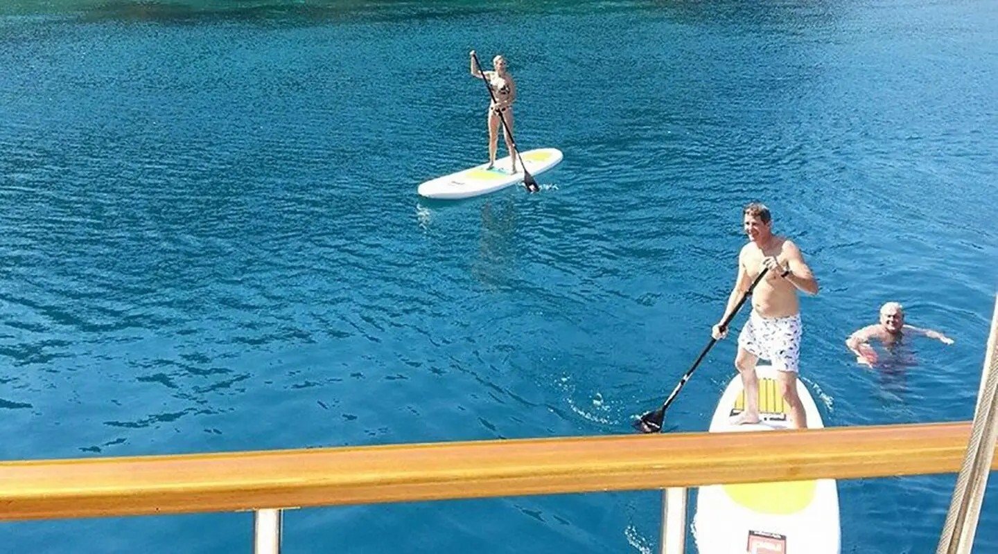 Two people on the water with a paddleboard and a kayak board in blue sea