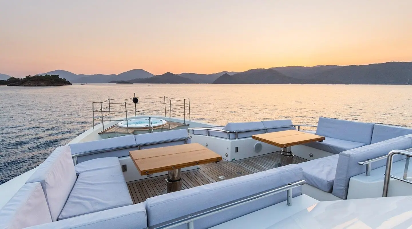 Takara One yacht bow deck with sun loungers over calm sea at sunset