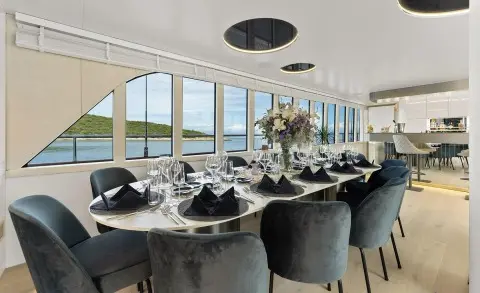Interior dining salon on Maxita yacht with large windows and round tables