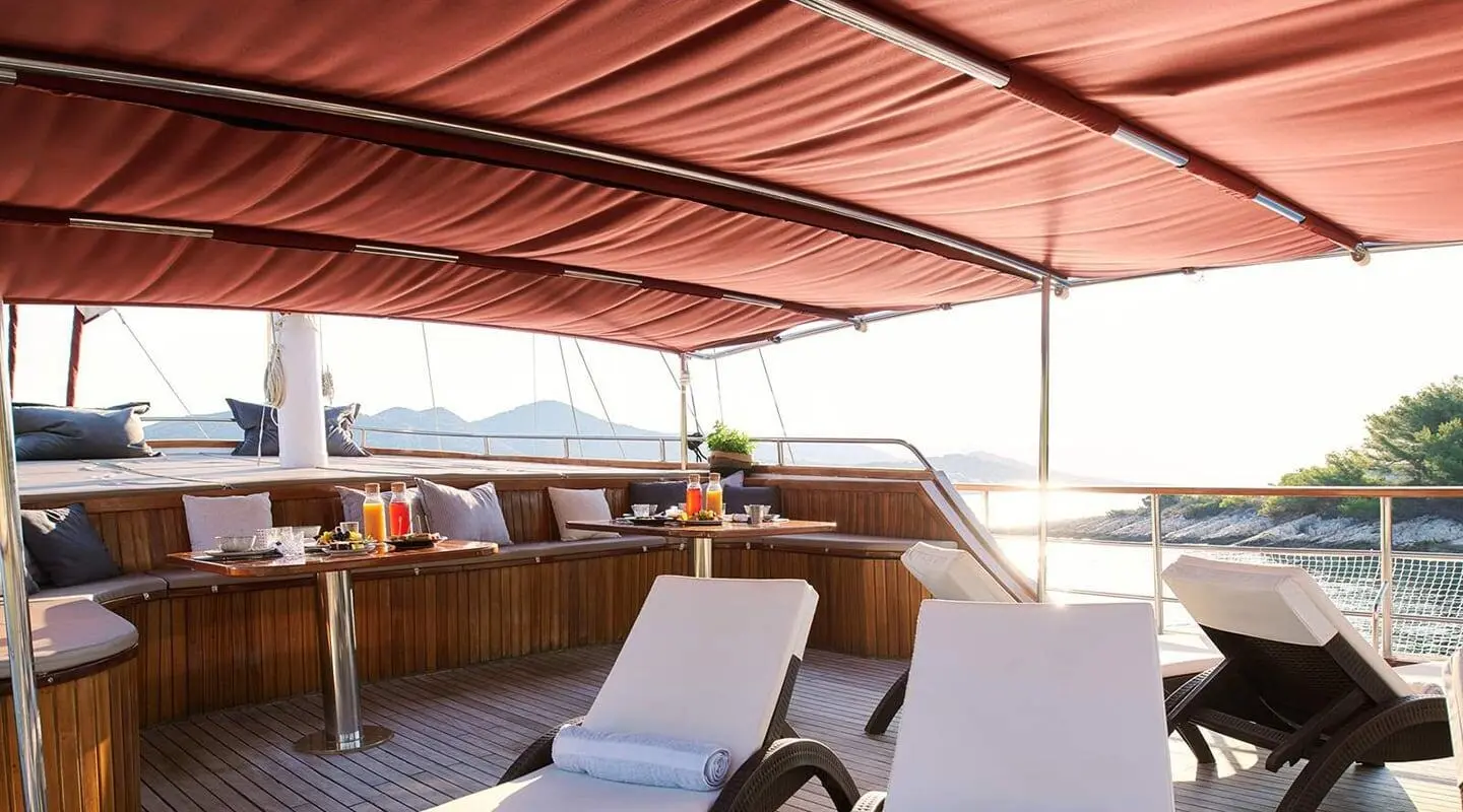Luxurious yacht cockpit with sun loungers and shaded seating at sunset