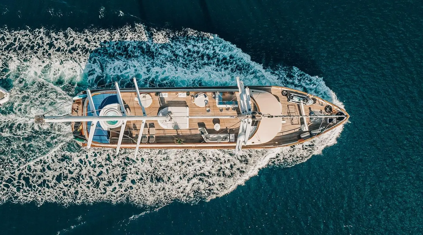 Top-down view of Maxita luxury yacht cruising coastline, sunlit deck