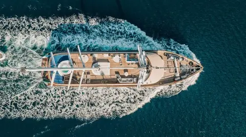 Top-down view of Maxita luxury yacht cruising coastline, sunlit deck