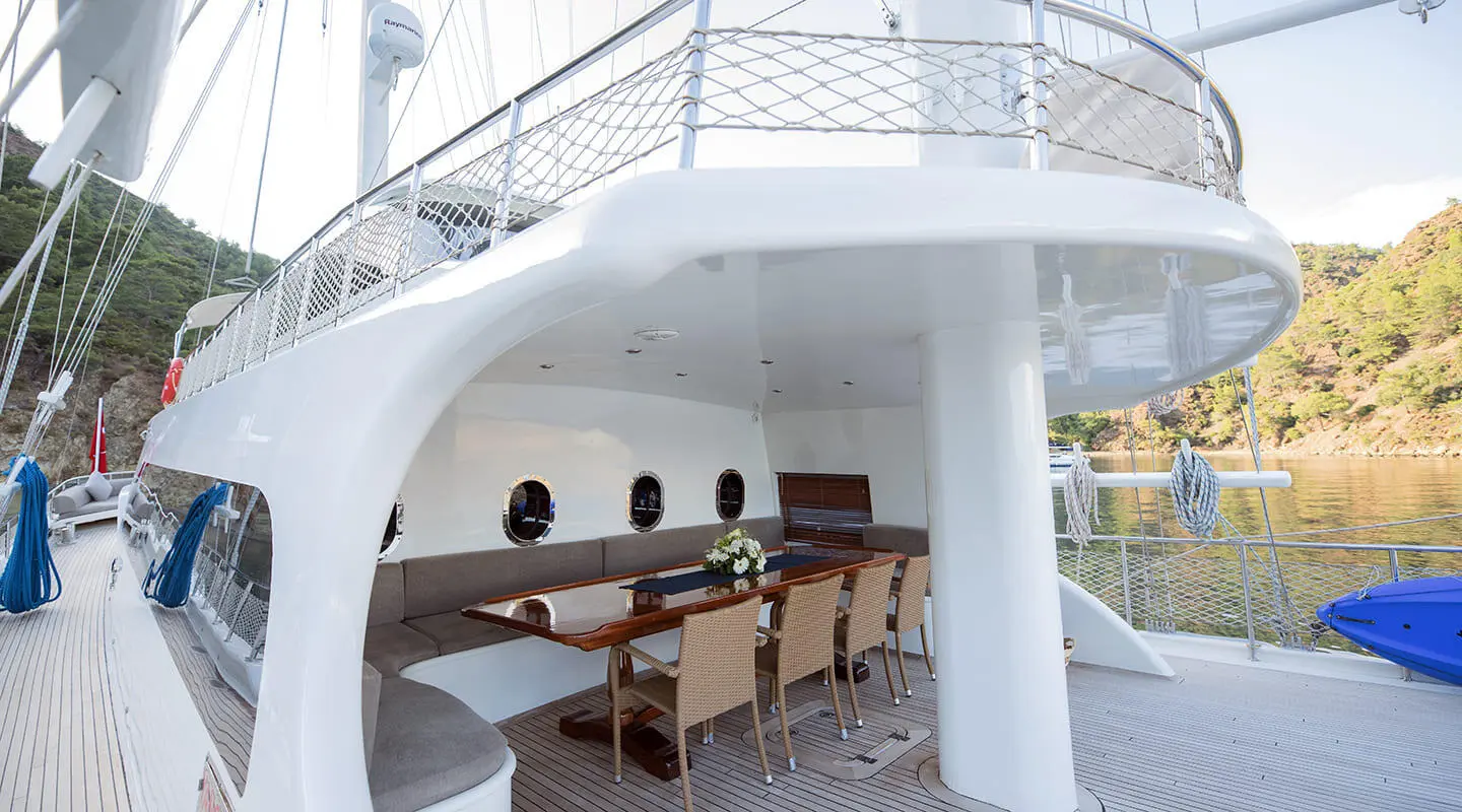 Kayhan 4 yacht charter: view of white hull, outdoor seating, and stairs at dusk