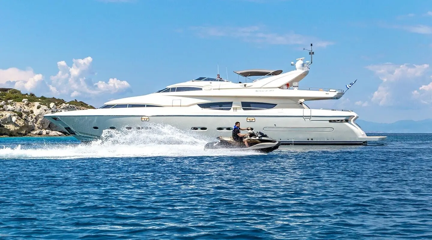 Luxurious white yacht named Divine slicing through blue sea with small motorboat nearby