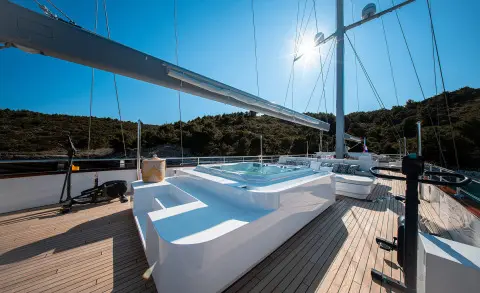 Nocturno motor yacht deck with white seating, sun loungers, and railing
