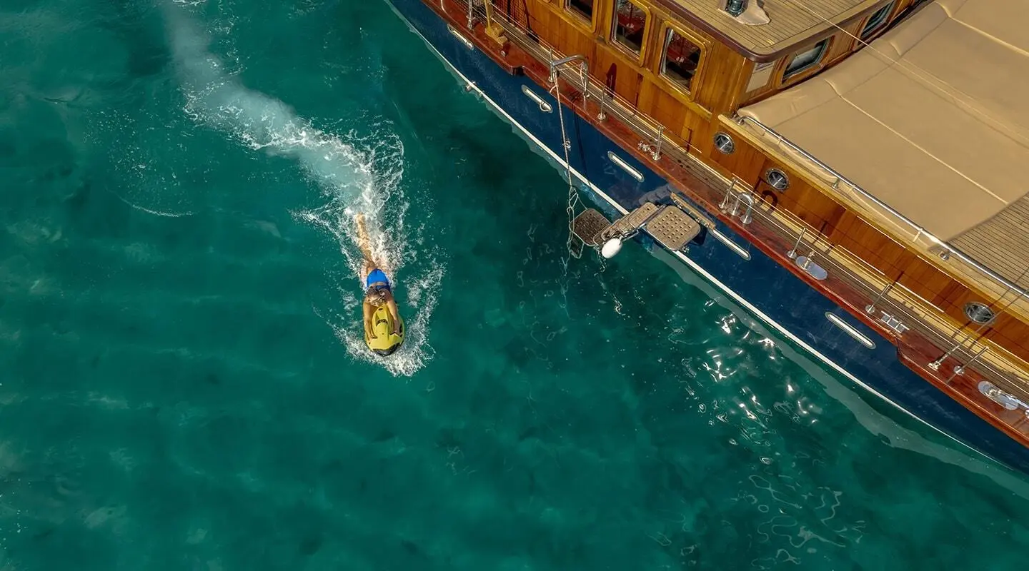 A yellow-hulled yacht named Smart Spirit docked near a wooden pier at sea dusk