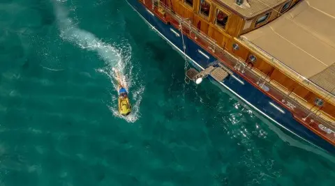 A yellow-hulled yacht named Smart Spirit docked near a wooden pier at sea dusk