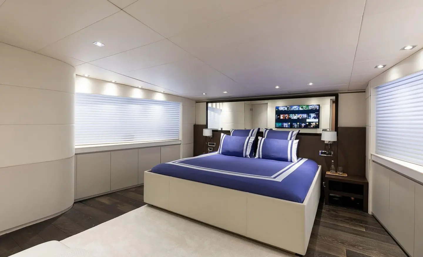 Modern master cabin with a blue bedding, large bed and TV screen at headboard