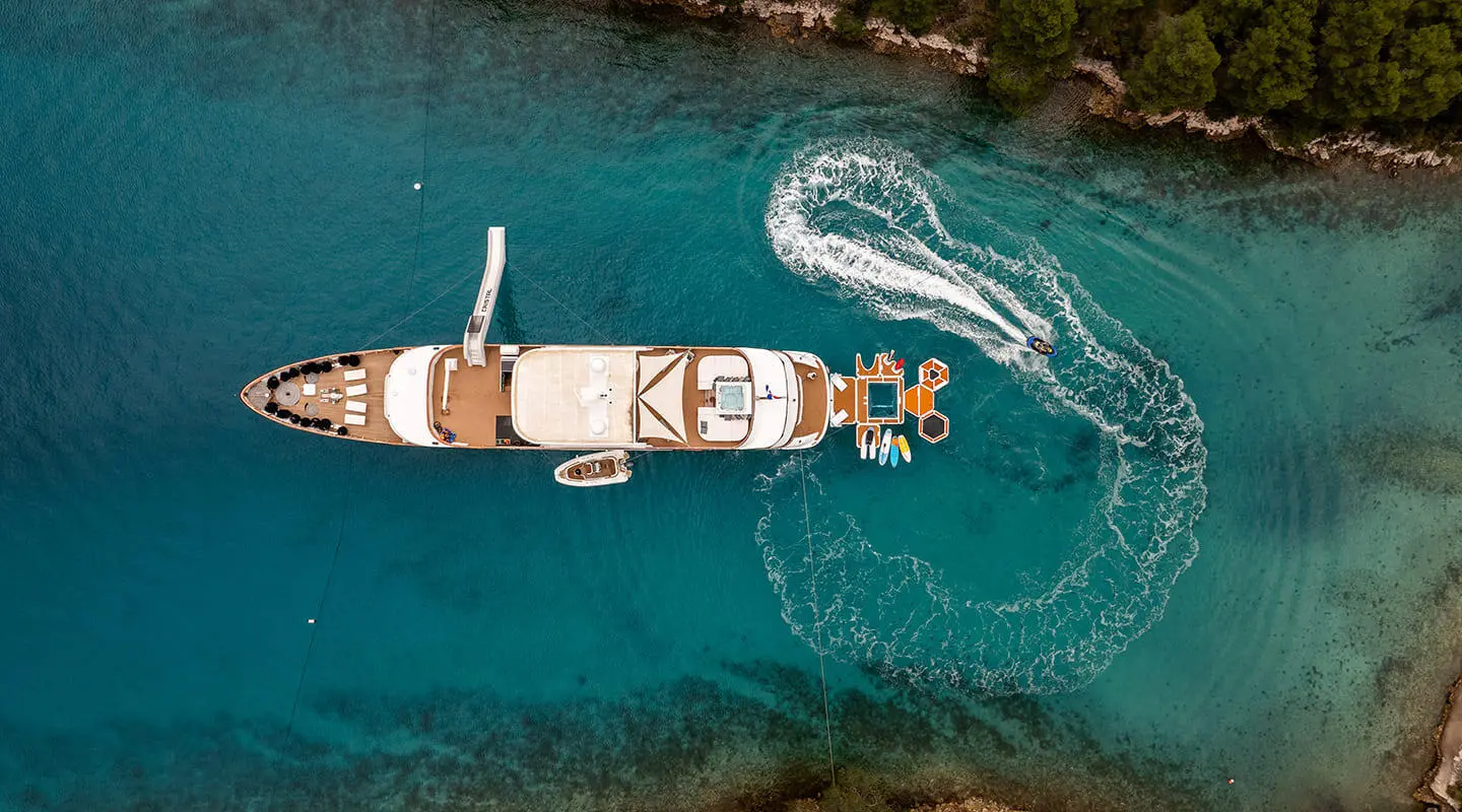 A luxury yacht named Cristal anchored in clear blue water at sunset