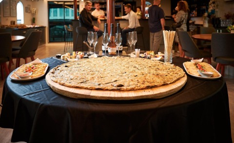 Large round table with sushi and appetizers laid out, on a yacht interior with people conversing in the background