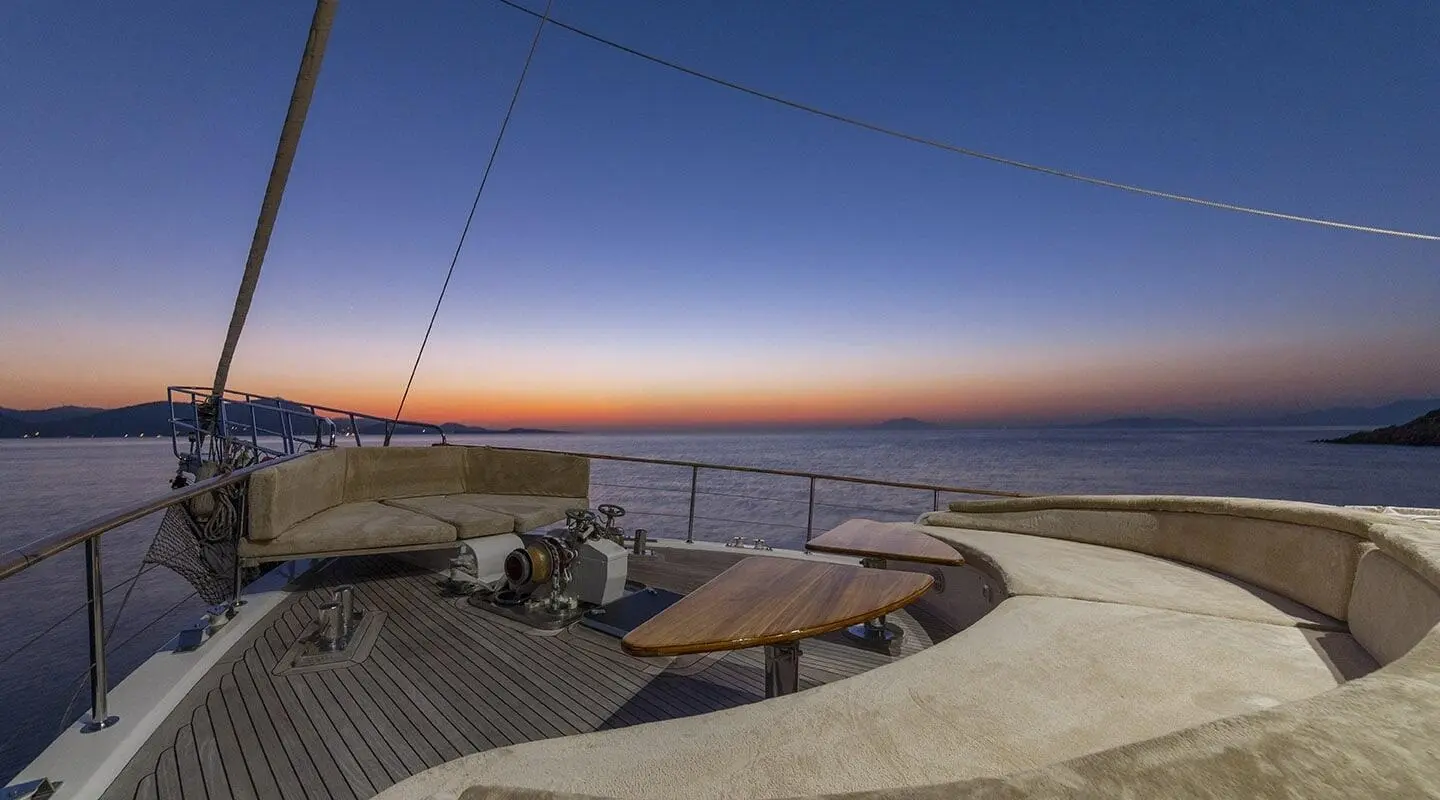 Sunset view on the deck with seating area and table, visible rigging and equipment