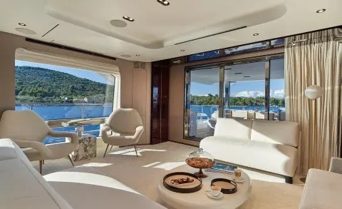 Aluminia Too yacht saloon at sunset with curved sofa, coffee table, and ocean view