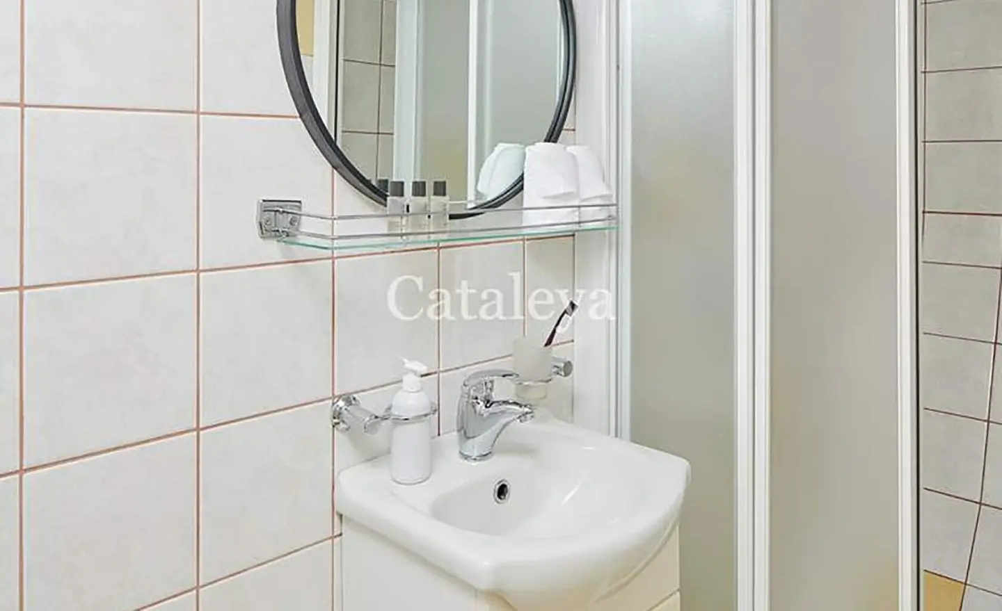 Cataleya gulet bathroom with white tiled walls, sink and round mirror