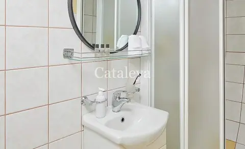 Cataleya gulet bathroom with white tiled walls, sink and round mirror