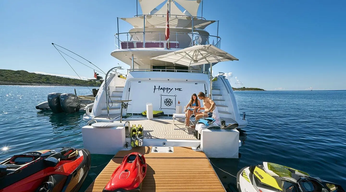 Yacht Happy Me docked with people on the rear deck and water backdrop