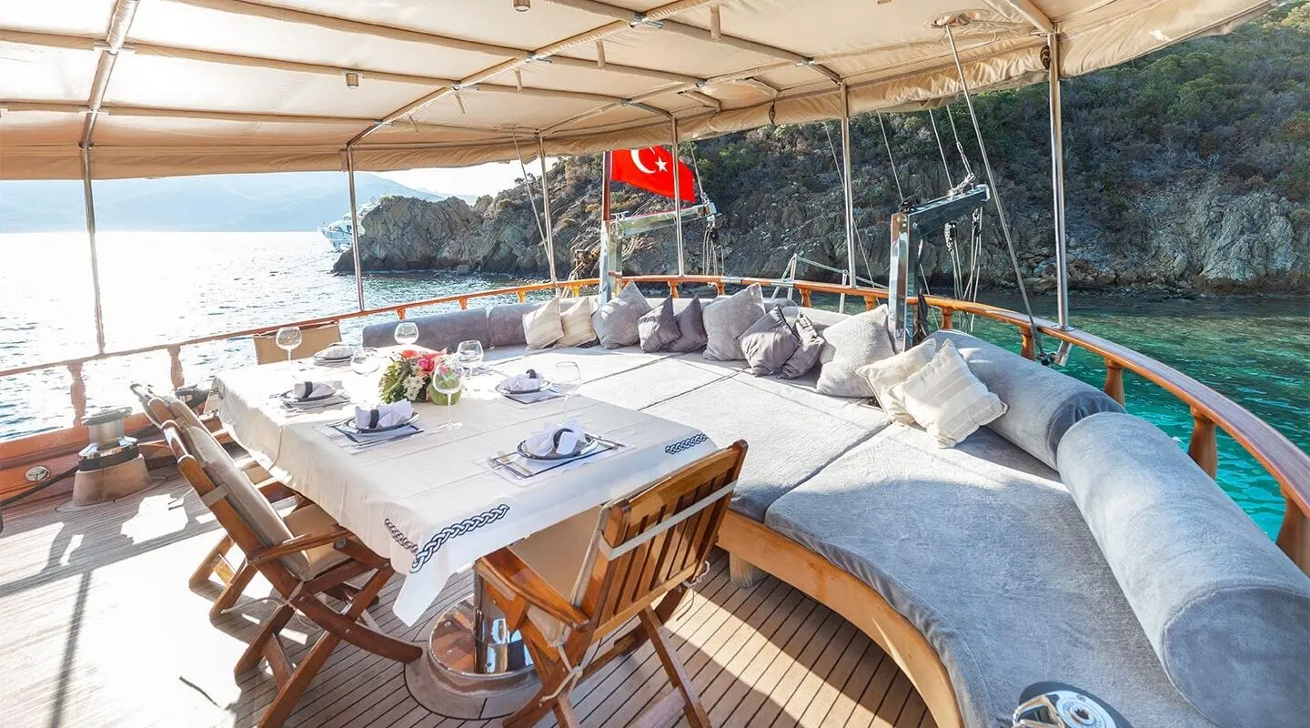 Aft deck on Ros Mare gulet with shaded seating, table set, and chairs