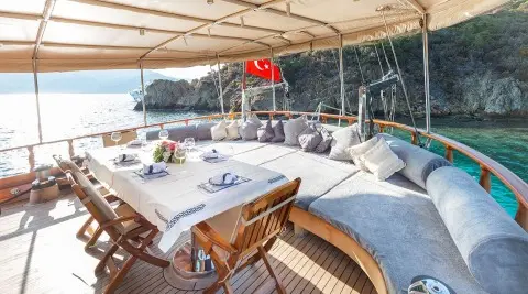 Aft deck on Ros Mare gulet with shaded seating, table set, and chairs