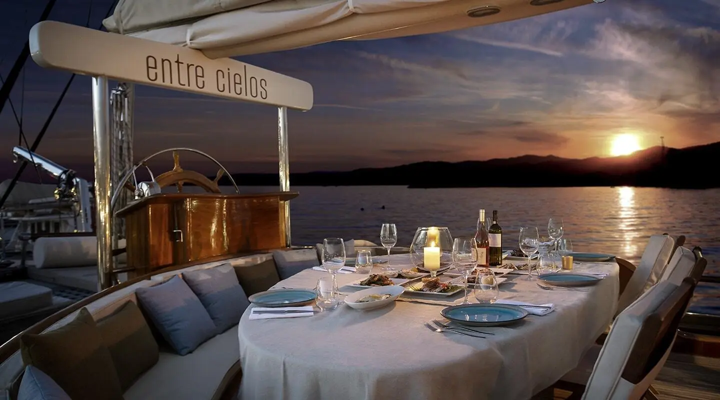 Entre Cielos yacht dining setup at sunset on a gulet with tableware and chairs