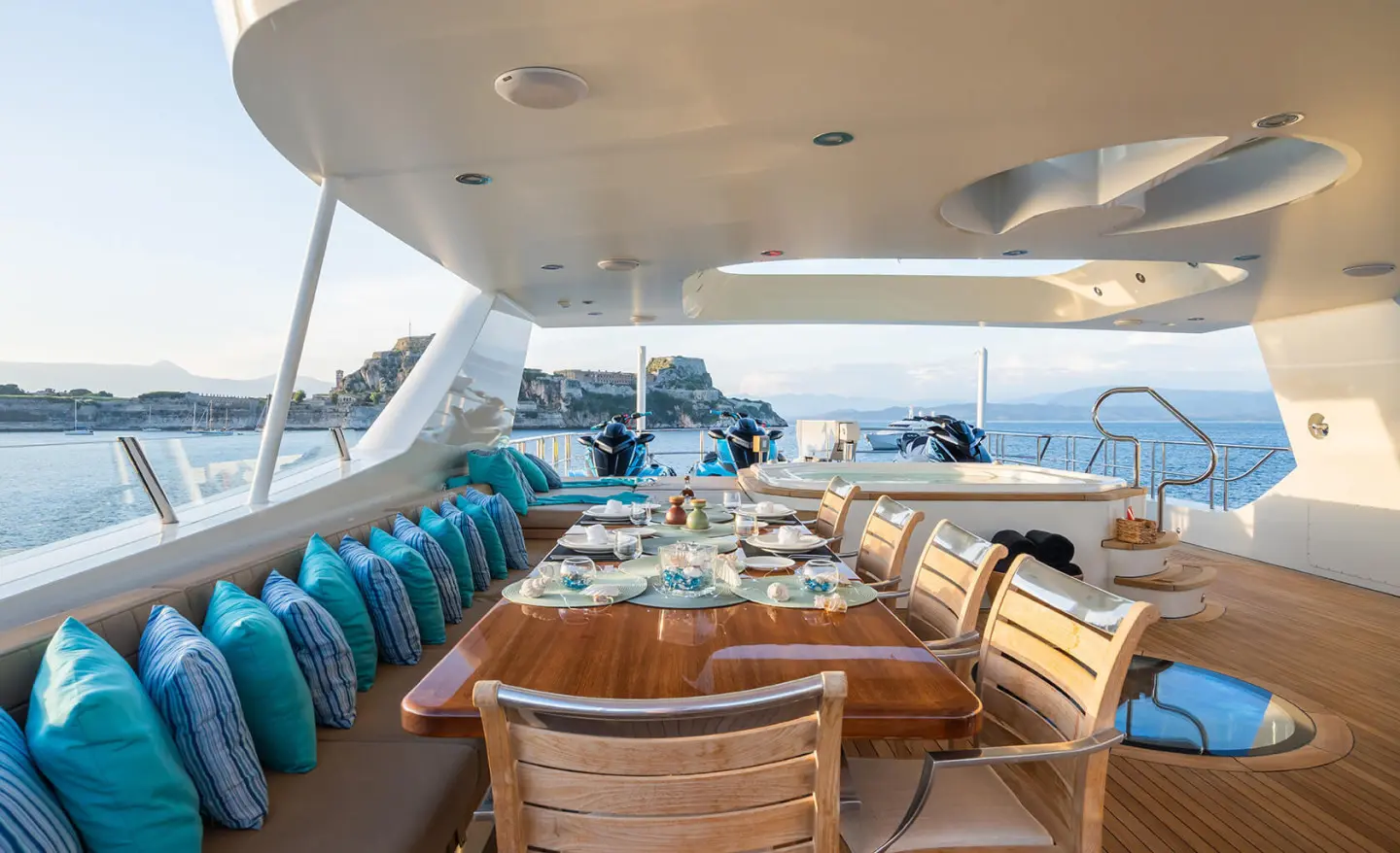 Serenity yacht deck dining area at sunset with wooden tables and blue cushions