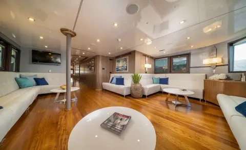 Luxurious yacht Olimp interior lounge with wood floors, curved seating, and a modern ceiling light