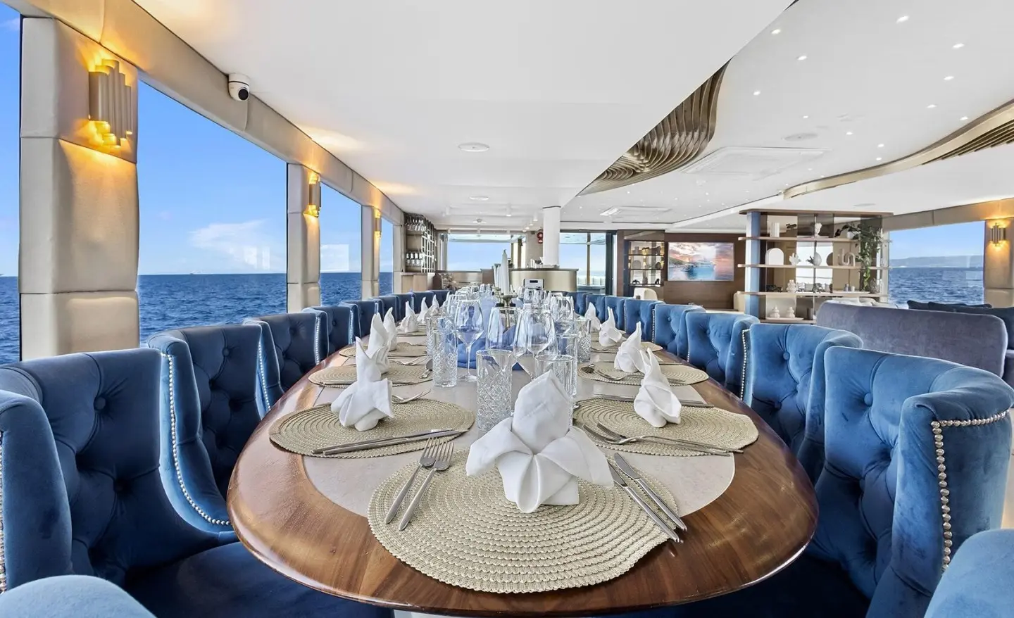 Interior: luxurious dining area on Bella yacht with round table set for guests