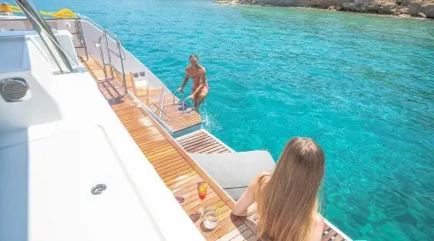 Deck view of D2 luxury yacht with people by the pool and blue sea
