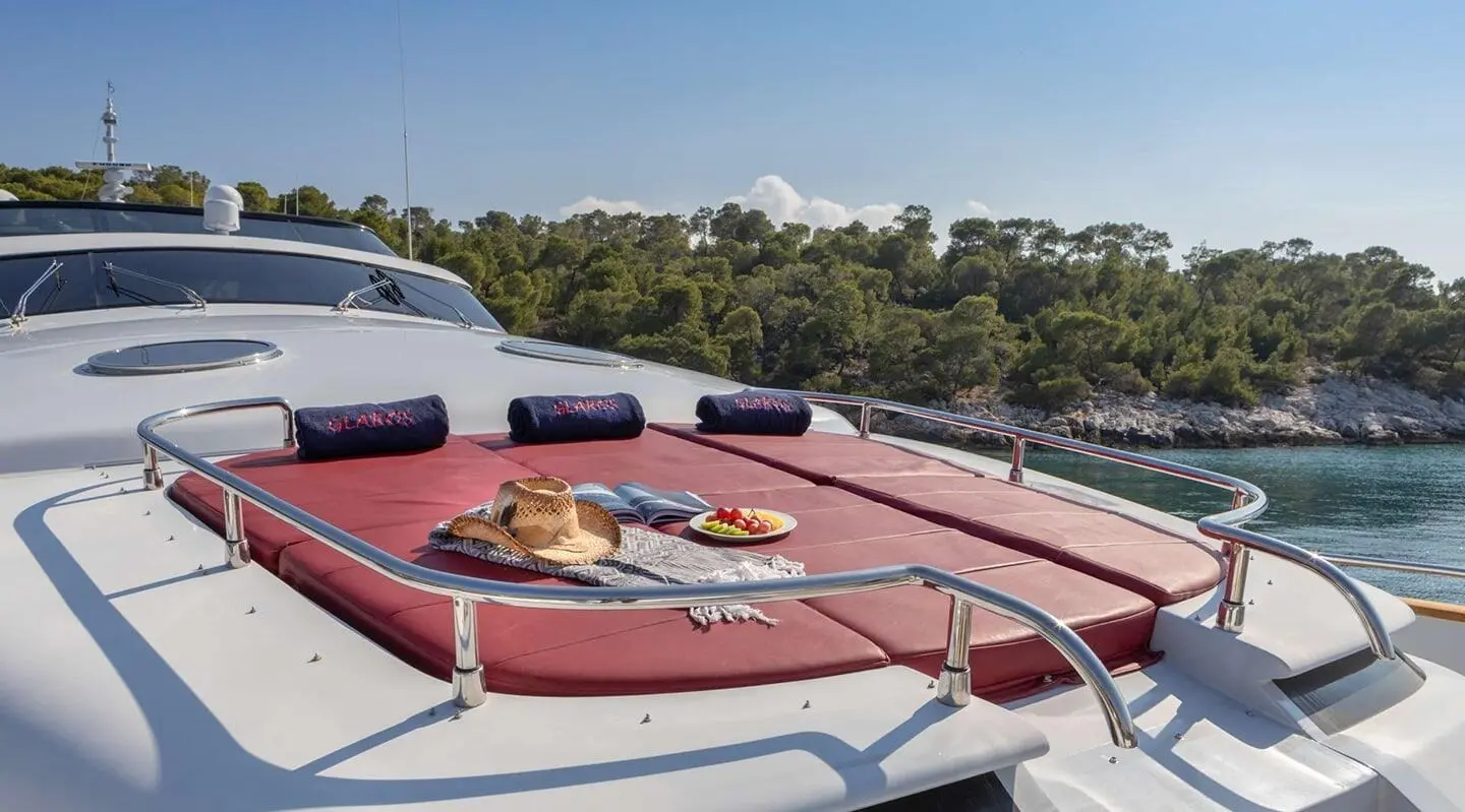 Glaros yacht deck with sunbathing cushions and plate of pastries at sunrise
