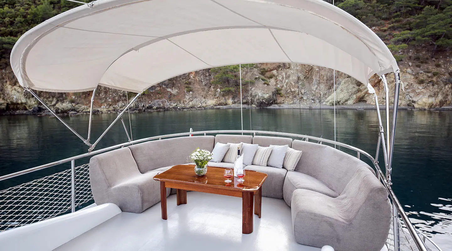 Kayhan 4 yacht lounge area: curved white seating with cushions and wooden table