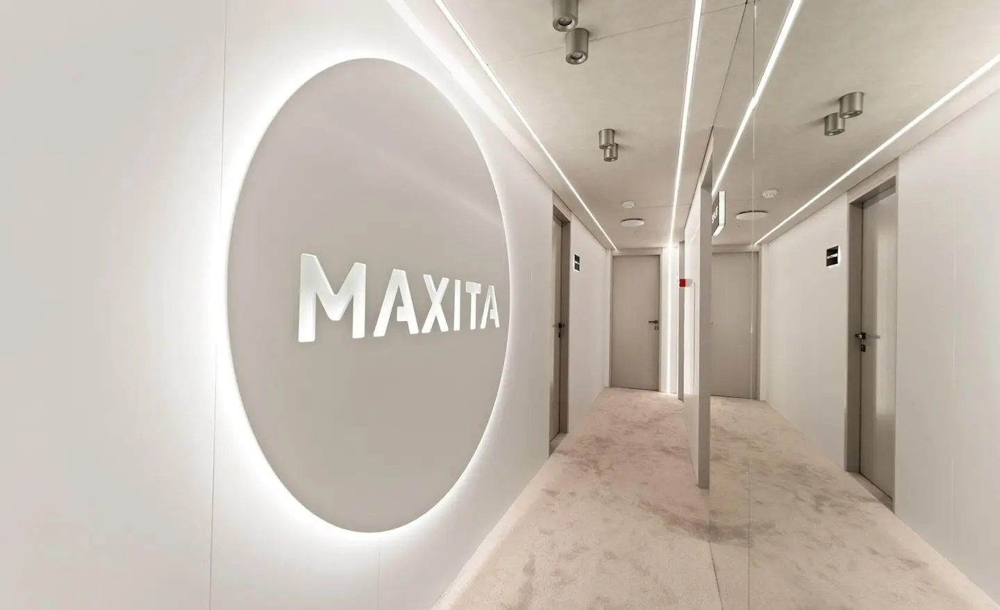 MAXITA logo on a circular wall in a modern white corridor
