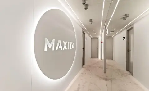 MAXITA logo on a circular wall in a modern white corridor