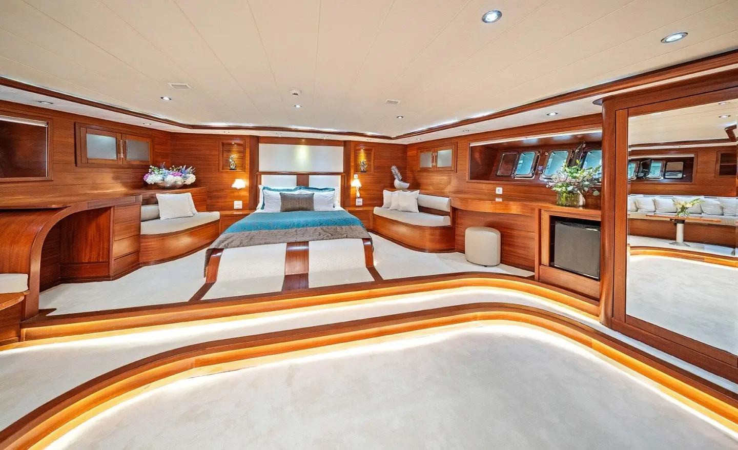 Interior yacht lounge with curved seating, polished wood, and large windows