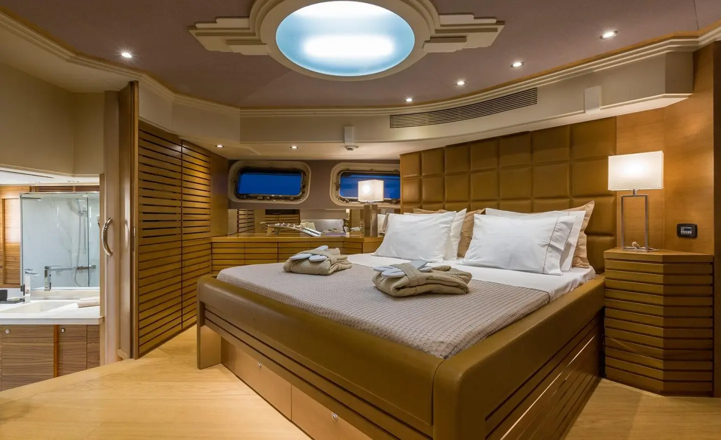 Aquarella yacht cabin with large bed, soft lighting, circular ceiling skylight, wooden accents