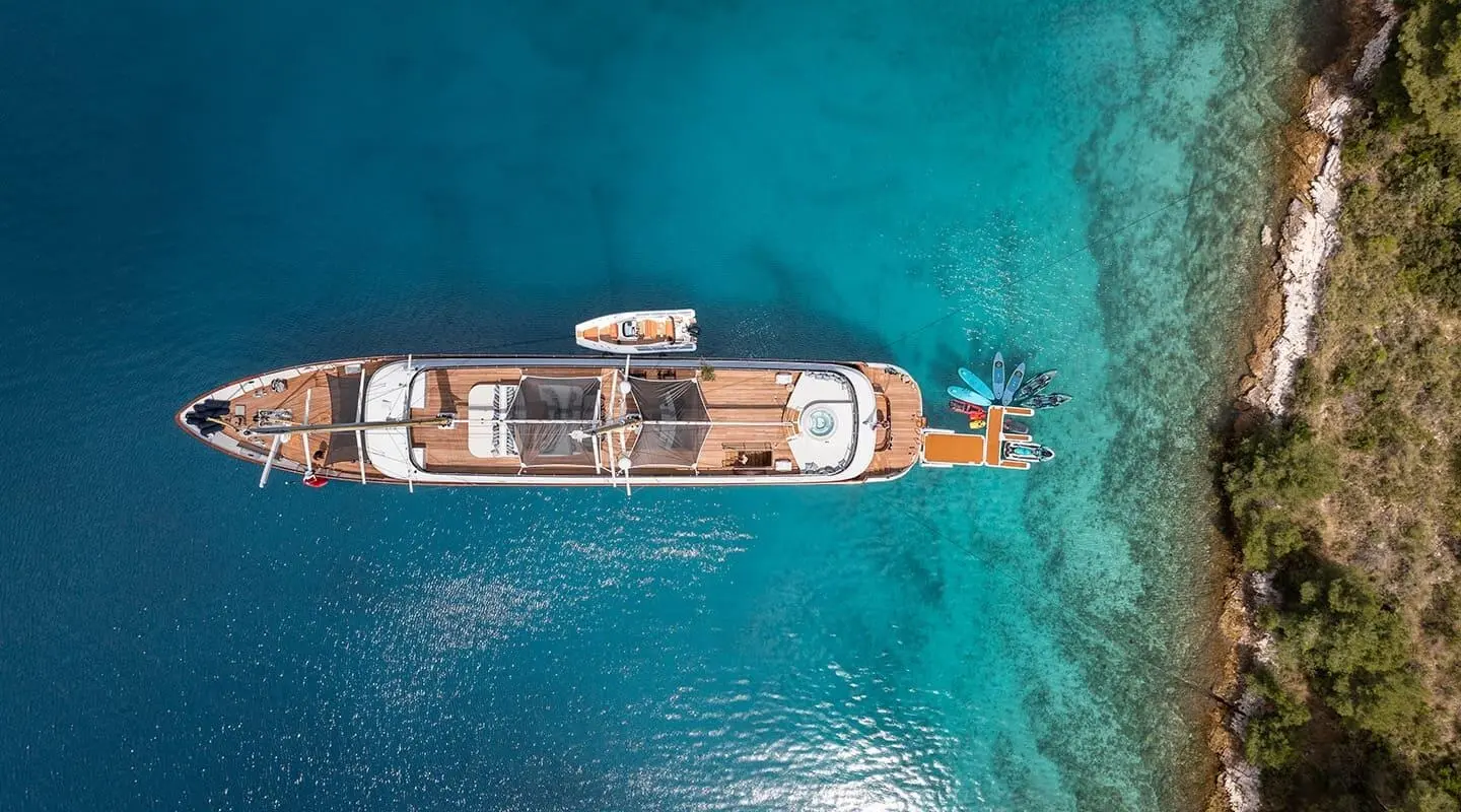 Top-down view of a sleek luxury yacht anchored in turquoise water