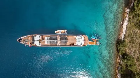 Top-down view of a sleek luxury yacht anchored in turquoise water