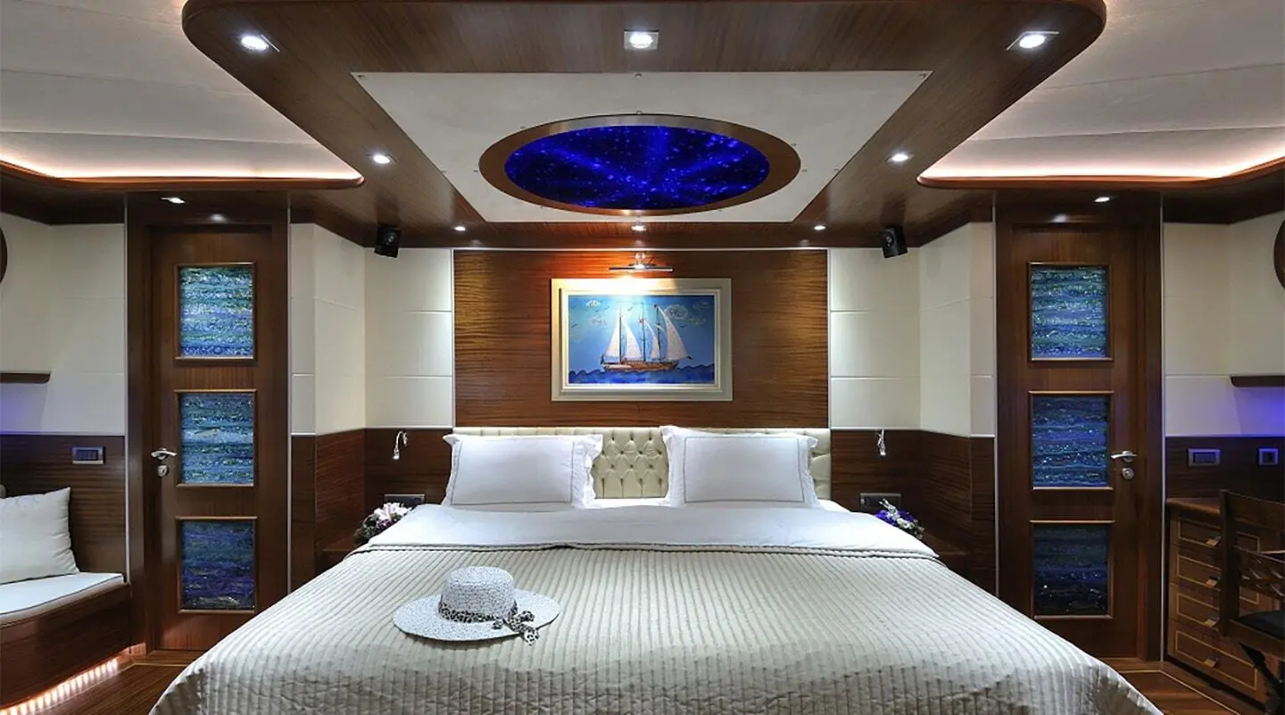 Dolce Mare yacht interior cabin with bed, overhead lighting, framed art, and porthole window