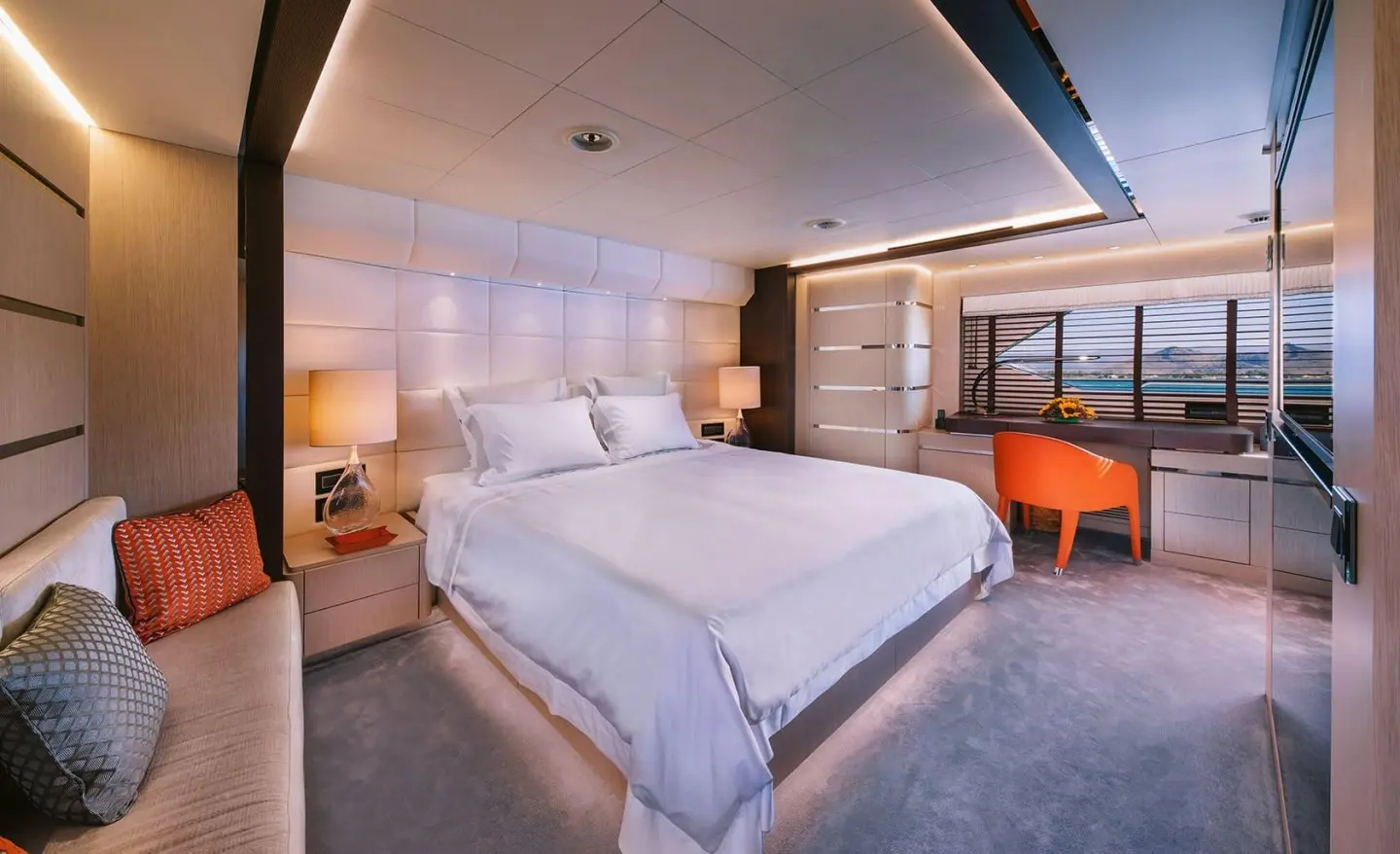 Xana yacht cabin with large bed, white linens, porthole window and wooden dresser