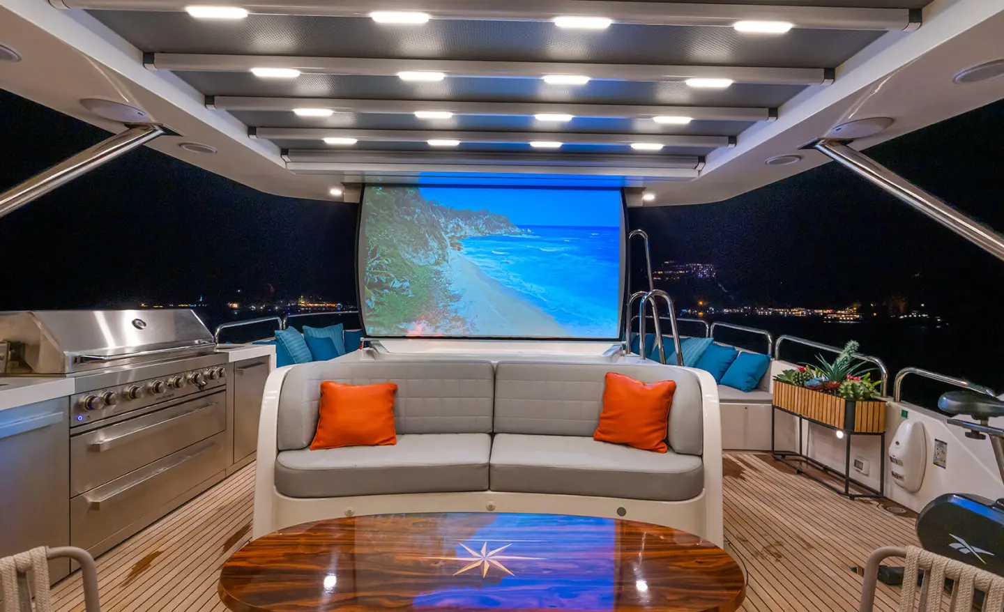 Amadea yacht cinema deck with sofa seating, projection screen, and blue lighting