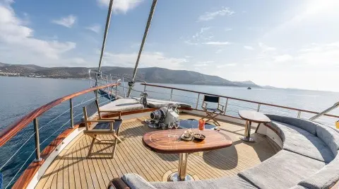 Gozdem The One yacht deck with wooden seating, table, and ocean view at sunset