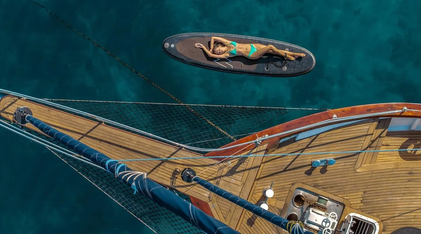 Smart Spirit yacht docked at sunset, teal water, small boat nearby, wooden dock railing
