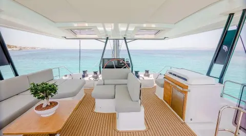 Astoria yacht at sunset, teak deck, white seating, stern view on calm sea