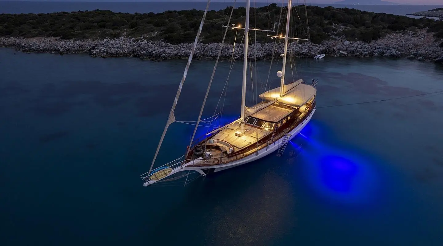 Arabella yacht anchored at dusk, sailboat silhouette on calm deep blue sea