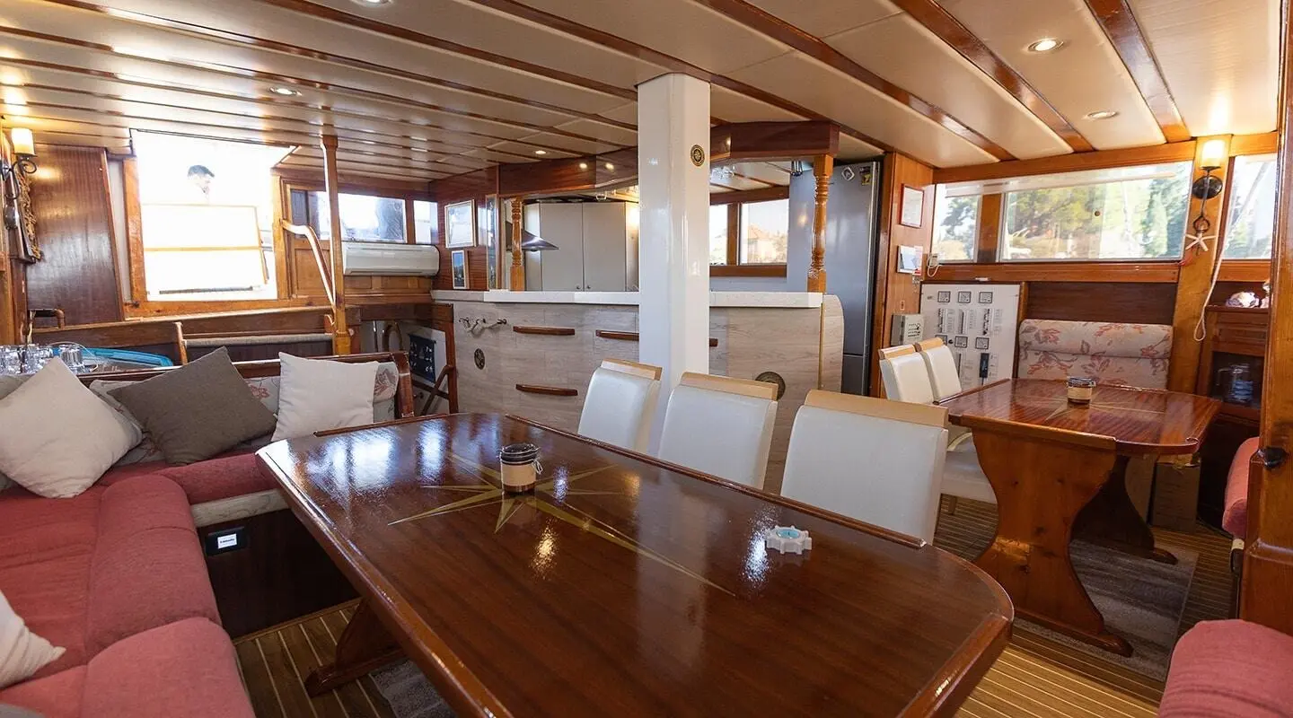 Inside Gardelin yacht with wooden dining area and cream seating