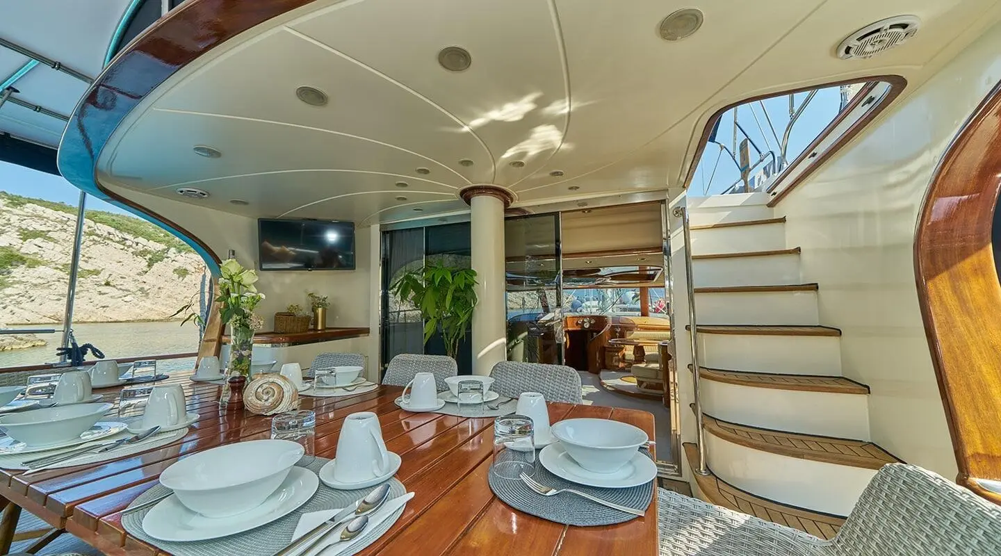 Gulet Lotus aft deck with round table settings and wooden flooring