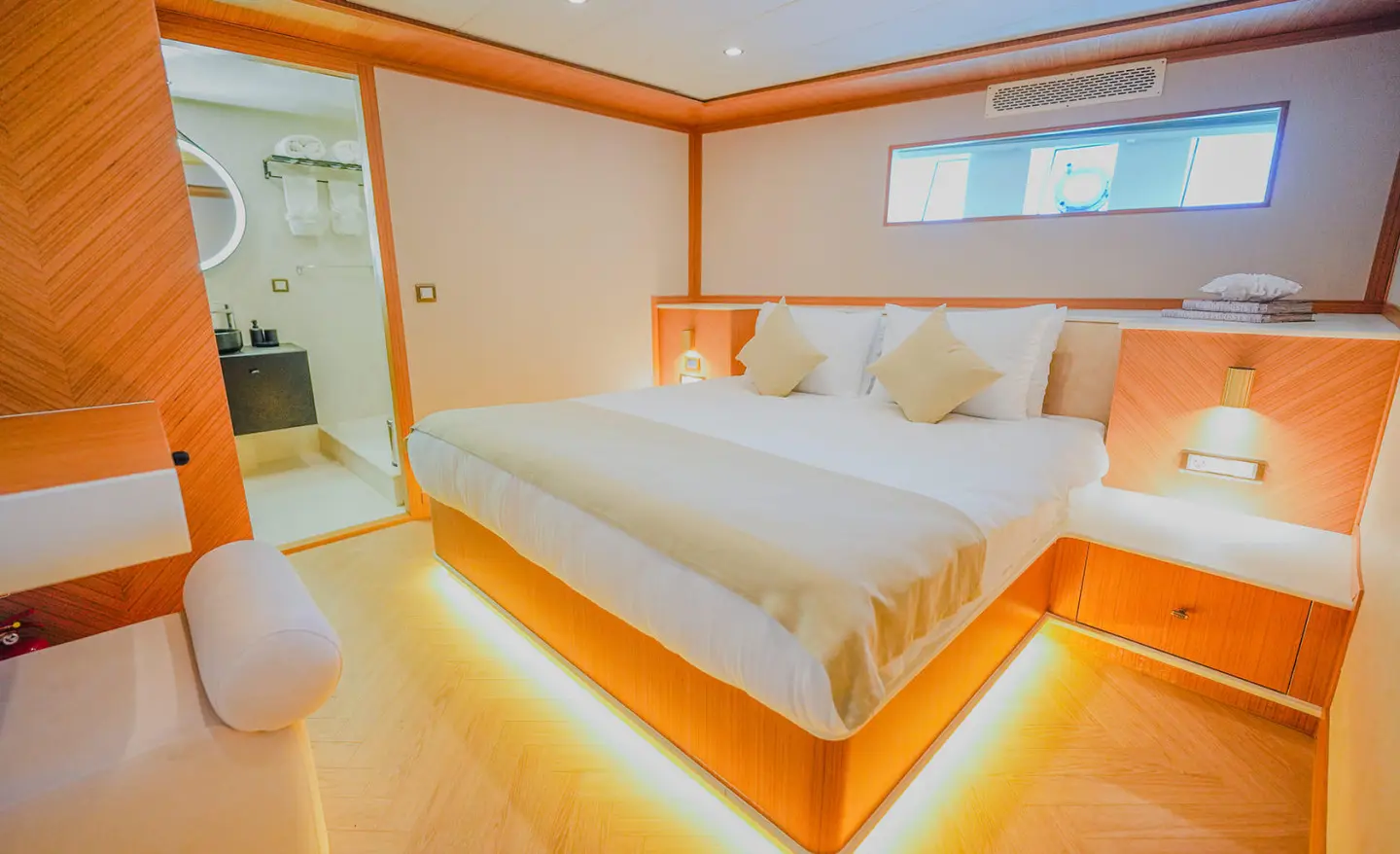 Luxurious king-size bed on a yacht cabin with warm LED lighting and windows