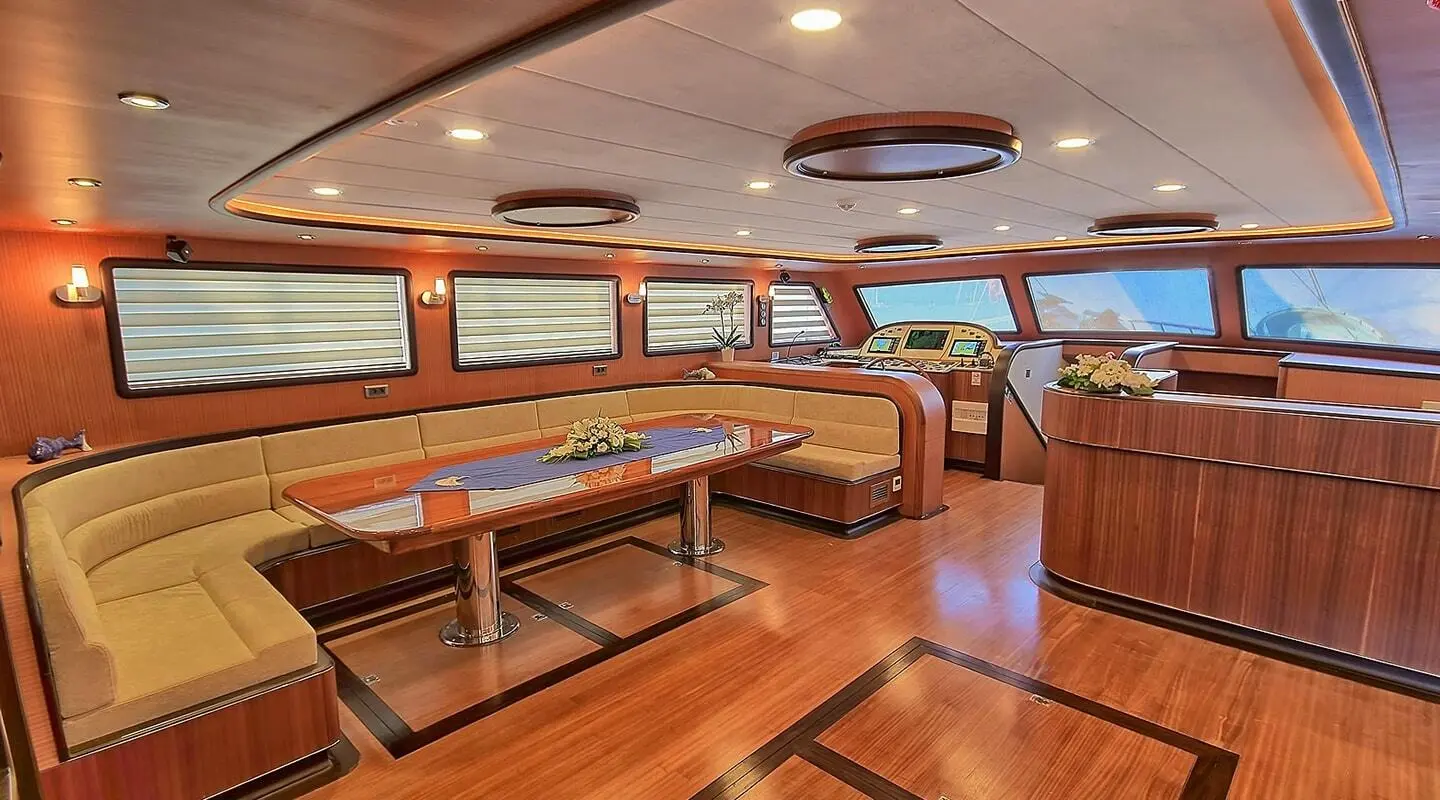 Queen Of Salmakis yacht interior: polished wooden deck, seating, windows, warm lighting