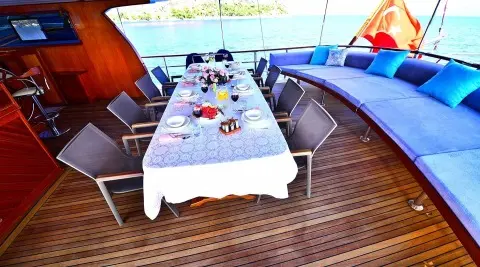 Gulet Maya aft deck with dining table set for guests and sunshade