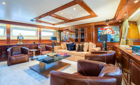Amadea yacht interior with brown leather seating and a central glass coffee table